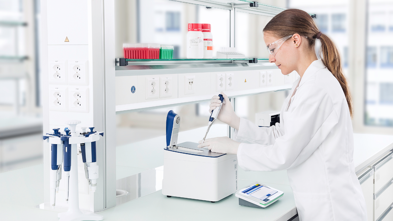 woman at a lab bench pipetting a sample into a spectrophotometer